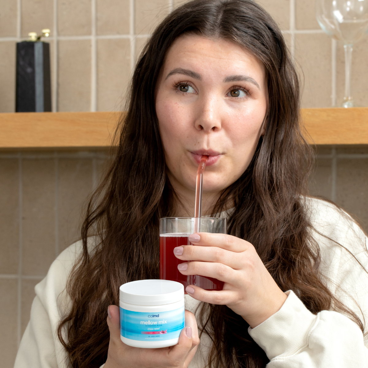 Woman looking rested, calm, and energized in her kitchen with a Calmd drink
